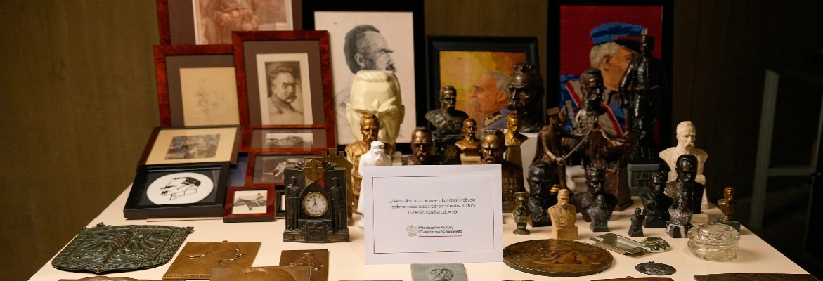 ułożone na stole przedstawienia Józefa Piłsudskiego: popiersia, zdjęcia, obrazy, rysunki